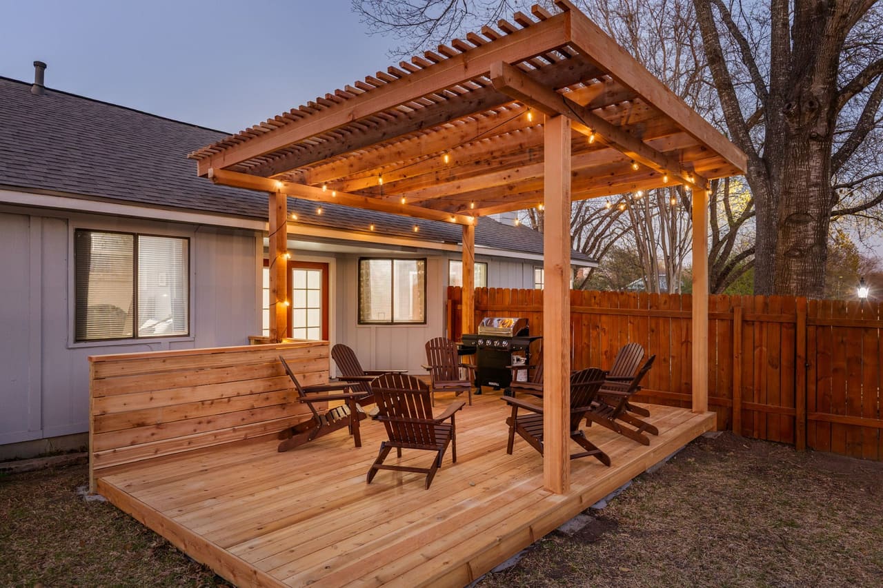Vinyl Nest backyard cedar deck with pergola and string lights at dusk